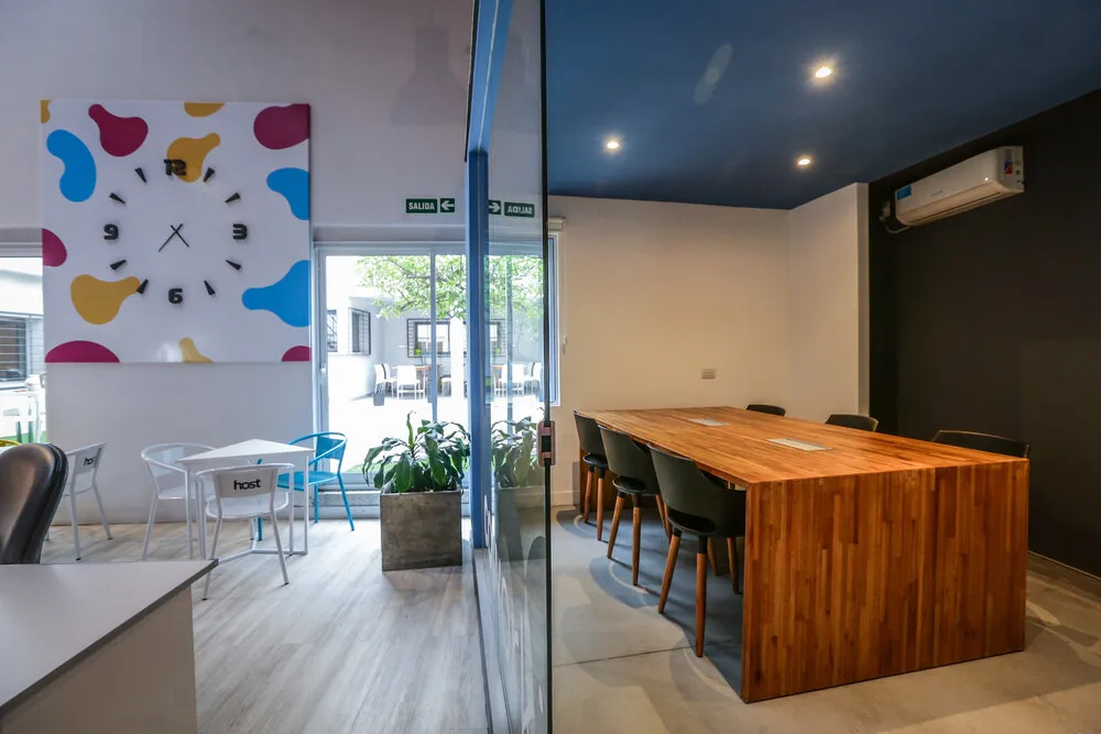 Sala de reuniones vidriada con mesa de madera en Host Orfeo