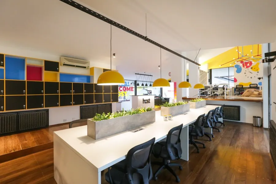 Mesa de coworking con lockers de colores y vista hacia la recepción